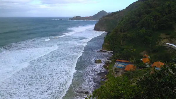 Tepeler, ağaçlar, kayalıklar, mercan resifleri ve Surumanis Sahili, Kebumen, Central Java 'daki denizden gelen dalgalarla birlikte kuş bakışı kıyı şeridi manzarası
