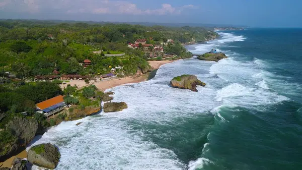 Kumsalın beyaz kum, mercan kayaları, ağaçlı tepeler, Drini Sahili Gunung Kidul Yogyakarta olarak bilinen okyanustan gelen dalgalar...