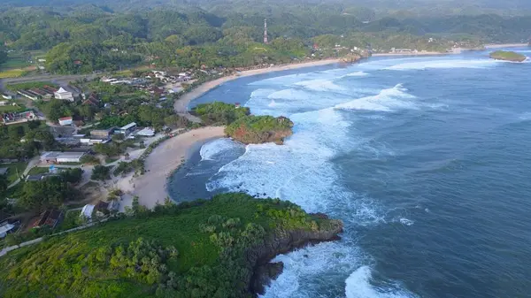 Beyaz kum, mercan kayaları, ağaçlı tepeler, Krakal Sahili Gunung Kidul Yogyakarta olarak bilinen okyanustan gelen dalgalar ile sahilin insansız hava aracı görüntüsü.