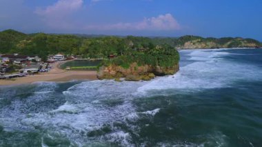 Beyaz kumlu plajlar, mercan kayaları, ağaçlı tepeler, okyanustan gelen büyük dalgalar ve Drini Sahili Gunung Kidul Yogyakarta olarak da bilinen akıntılar.