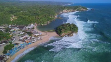 Beyaz kumlu plajlar, mercan kayaları, ağaçlı tepeler, okyanustan gelen büyük dalgalar ve Drini Sahili Gunung Kidul Yogyakarta olarak da bilinen akıntılar.