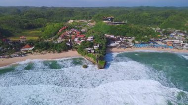Beyaz kumlu plajlar, mercan kayaları, ağaçlı tepeler, okyanustan gelen büyük dalgalar ve Drini Sahili Gunung Kidul Yogyakarta olarak da bilinen akıntılar.