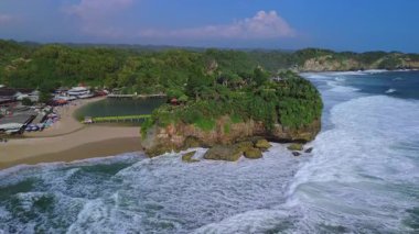 Beyaz kumlu plajlar, mercan kayaları, ağaçlı tepeler, okyanustan gelen büyük dalgalar ve Drini Sahili Gunung Kidul Yogyakarta olarak da bilinen akıntılar.