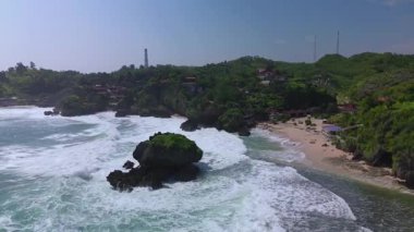 Mbuluk Sahili 'nin insansız hava aracı görüntüsü Gunung Kidul Yogyakarta tepeleri, beyaz kumları, mercan kayalıkları ve ünlü bir turizm merkezi olan okyanus dalgalarıyla dolu bir plaj.