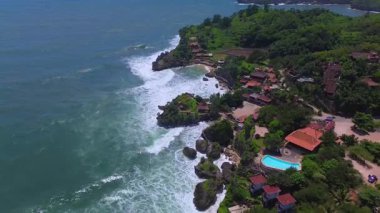 Mbuluk Sahili 'nin insansız hava aracı görüntüsü Gunung Kidul Yogyakarta tepeleri, beyaz kumları, mercan kayalıkları ve ünlü bir turizm merkezi olan okyanus dalgalarıyla dolu bir plaj.