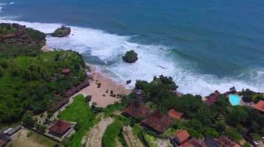 Mesra Sahili 'nin insansız hava aracı görüntüsü Gunung Kidul Yogyakarta tepeleri, beyaz kumları, mercan kayalıkları ve ünlü bir turizm merkezi olan okyanus dalgalarıyla dolu bir plaj.