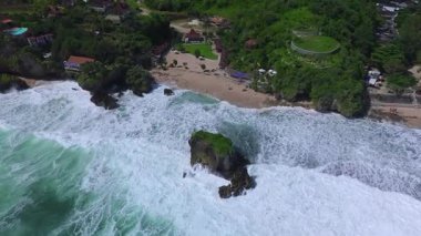 Mesra Sahili 'nin insansız hava aracı görüntüsü Gunung Kidul Yogyakarta tepeleri, beyaz kumları, mercan kayalıkları ve ünlü bir turizm merkezi olan okyanus dalgalarıyla dolu bir plaj.