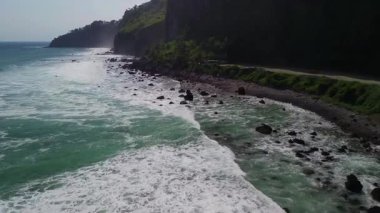 Menganti Sahili, Kebumen, Central Java, Endonezya 'nın insansız hava aracı manzarası, ağaçlar, mercan resifleri ve okyanustan gelen dalgalarla çevrili bir turizm merkezi.