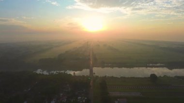 Hava aracı görüntüsü dramatik gün doğumu ve sabah altın saati, tarımsal arazisi olan kırsal bir alanda, ortada bir otoyol ve nehri geçen bir köprü ile.