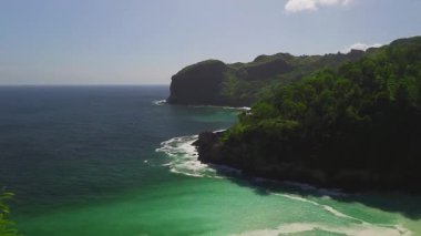 Öğleden sonra Sawangan, Kebumen, Central Java, Endonezya 'daki sahil şeridinde okyanus manzaralı ve mercan kayalıklarına çarpan dalgaların insansız hava aracı uçuşu.