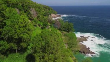 Öğleden sonra Sawangan, Kebumen, Central Java, Endonezya 'daki sahil şeridinde okyanus manzaralı ve mercan kayalıklarına çarpan dalgaların insansız hava aracı uçuşu.