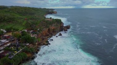 Ngobaran Sahili, Gunung Kidul, Yogyakarta 'nın insansız hava aracı görüntüsü dalgaları, mercan resifleri ve üzerinde bir Hindu tapınağı olan turistik bir sahil..