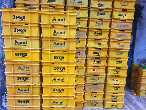 Mumbai, Maharashtra, Hindistan - Kasım 2024: Amul süt kutularının depolanması ve taşınması amaçlanan büyük bir yığın sarı plastik tepsi.