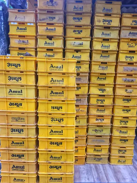Mumbai, Maharashtra, Hindistan - Kasım 2024: Amul süt kutularının depolanması ve taşınması amaçlanan büyük bir yığın sarı plastik tepsi.