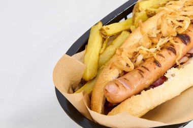 Kızarmış patates ve kızarmış soğanlı sosisli sandviç.