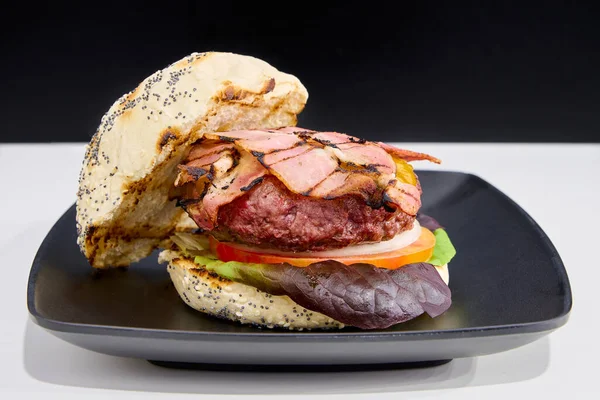 hamburger with bacon, cheese, tomato and purple lettuce