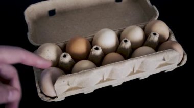 A man's hand opens an egg tray and takes one. Close-up