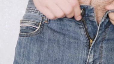 The man puts a condom in the front pocket of his jeans. Close-up