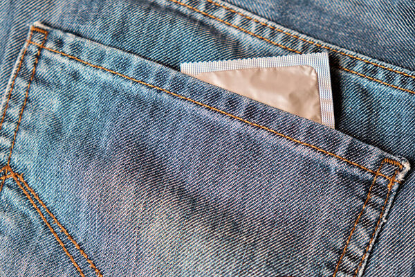 A condom in a blister looks out of the back pocket of jeans.