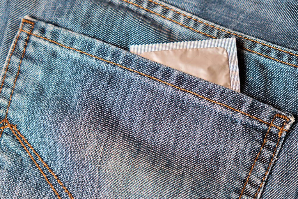 A condom in a blister looks out of the back pocket of jeans.