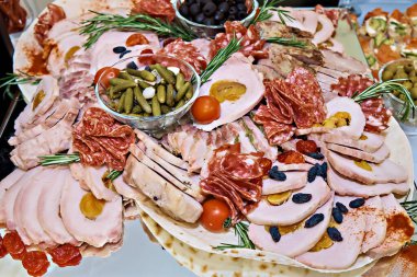 Meat cutlet, chicken roll, pickles, sausage. Banquet table.
