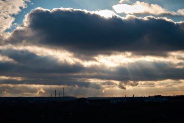 The winter rays of the sun break through thick gray clouds.
