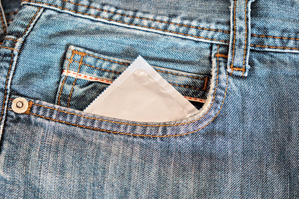 A condom in a blister looks out pocket of jeans.