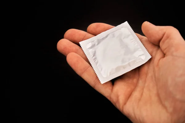 Mężczyzna Trzyma Prezerwatywy Otwartej Dłoni Ciemnym Tle Koncepcja Bezpiecznego Seksu — Zdjęcie stockowe