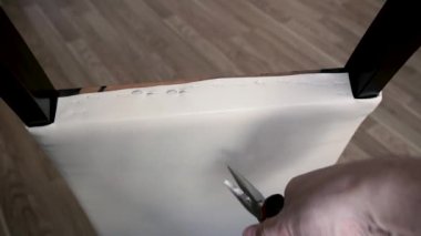 Koltuğun döşemesini söküyorum. Bir adam pense kullanarak zımbaları çıkarır..