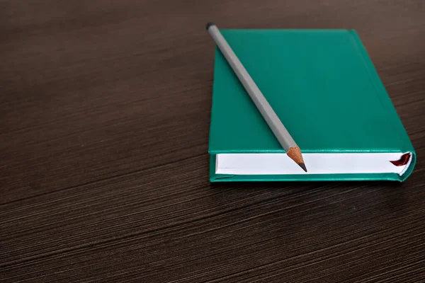 stock image A business notebook with a pencil lie on a dark table.