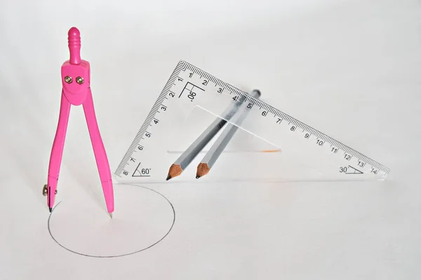 A drawing compass and a triangular ruler with two pencils in the middle of the ruler, on a white background. View from above.