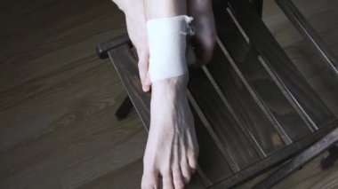 Genç bir adam ayak bileğine elastik bandaj yapıştırıyor. Tıbbi konular. Yakın plan..