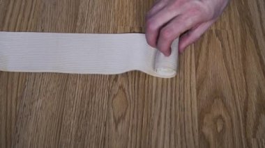 Bir adam elastik bandajı rulo haline getiriyor. Tıbbi konular. Yakın plan..