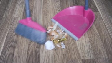 Bir adam evi süpürge ve kürekle süpürüyor, evden çöp topluyor..