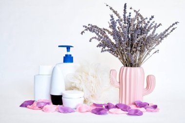 Beyaz arka planda bir vazoda şampuan, krem, bez, parfüm ve lavanta tozu seti. Spa prosedürleri.