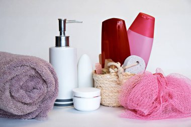 Pembe bez, şampuan, sıvı sabun, aromatik banyo yaprakları, ayaklar için bir fırça ve sünger taşı ile bir sepet ve diğer tuvalet malzemeleri.