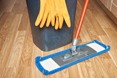 Koruyucu eldivenli bir kova ve yerleri silmek için paspas..