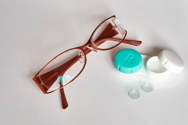 Contact lenses with a container and glasses on a white background. View from above. The topic of medicine and health care.