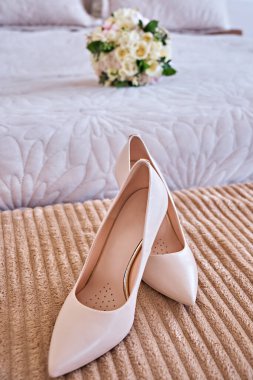Gelin ayakkabıları ön planda, düğün buketi arka planda odaklı değil..
