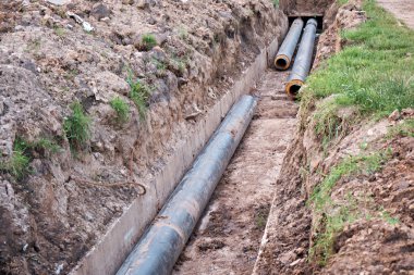 Laying new water pipes in a concrete ditch. Thermal line. clipart