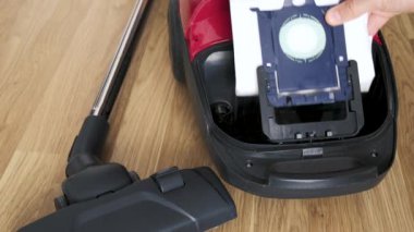 İnsanlar yeni bir çöp torbasını elektrik süpürgesine sokuyor..
