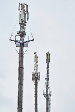 Bulutlu bir gökyüzünün arka planında telekomünikasyon kuleleri.