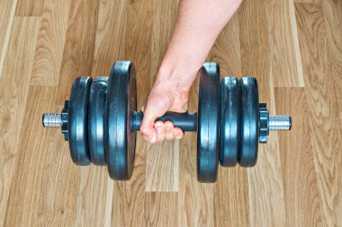 Bir adamın eli yerde duran bir dambılı kavradı..