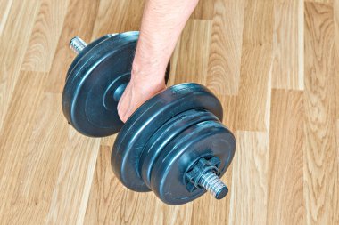 Bir adamın eli yerde duran bir dambılı kavradı..