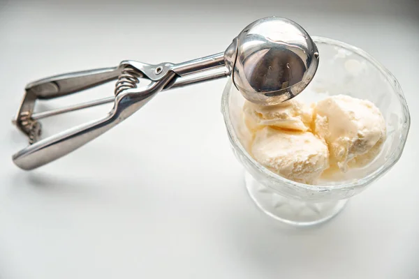 Scoops of ice cream in a glass jar and a dispenser-spoon for ice cream.