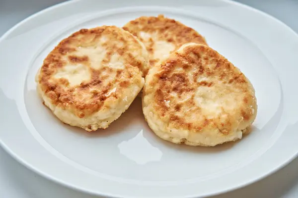 Homemade cheese pancakes or cheese pancakes lying on a white plate.