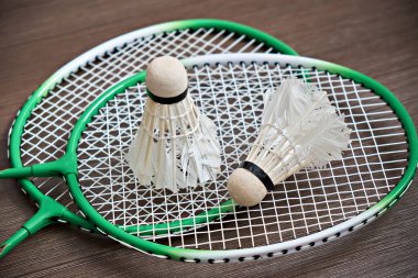 Badminton raketlerinin üzerinde iki mekik horozu yatıyor. Profesyonel spor ekipmanları.
