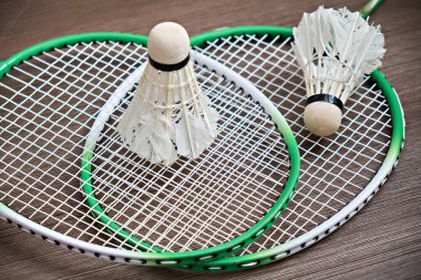 Badminton raketlerinin üzerinde iki mekik horozu yatıyor. Profesyonel spor ekipmanları.
