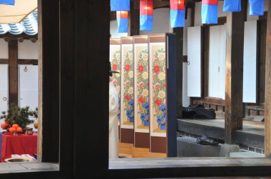 SEOUL, Güney Kore - 23 Ekim 2022: Tanımlanamayan yaşlı Koreli asilzade siyah bir şapka takıyor ve geleneksel Hanok köyünde geleneksel duvar odası ayırıcılarının önünde duruyor.