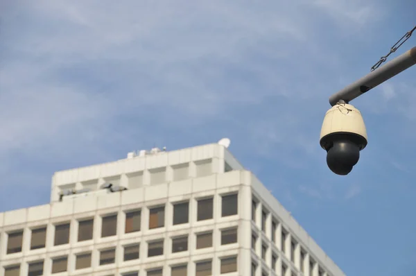 CCTV security camera with blue sky and white office building to monitor crimes and accidents 24/7 in the city center